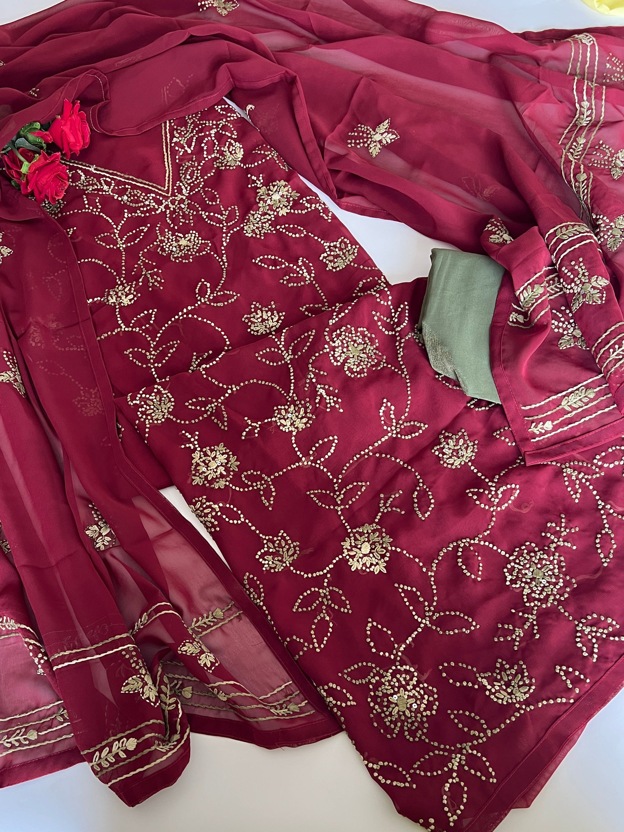 A deep maroon red ethnic suit set with intricate gold floral embroidery, featuring a kurta, matching dupatta, and olive green bottom fabric piece Unstitched suit