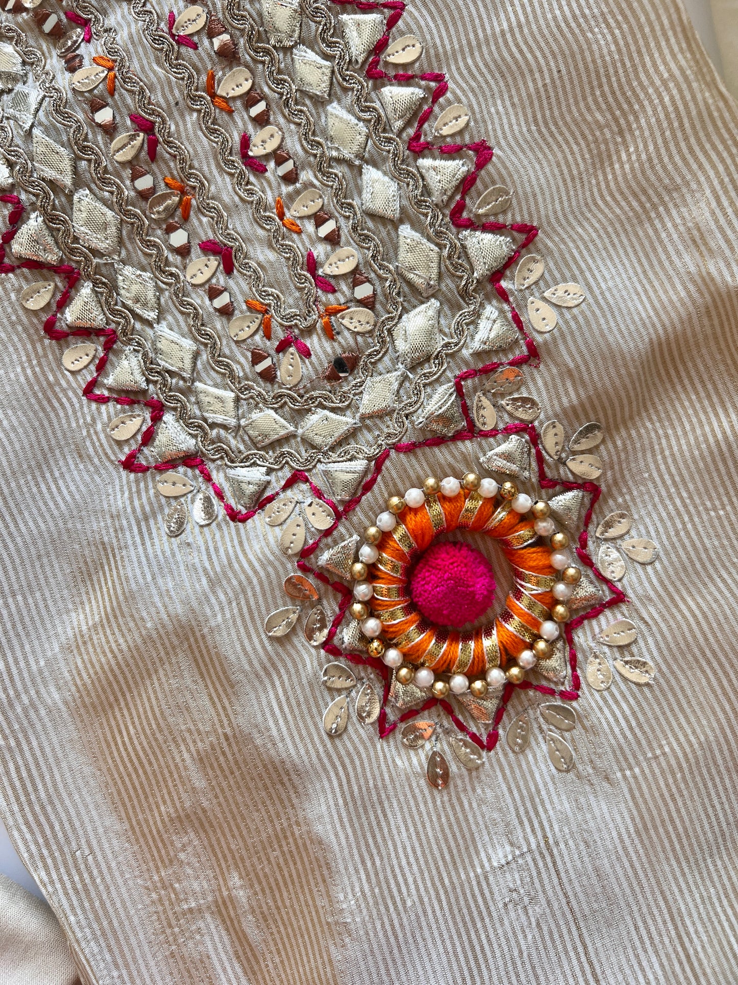 Festive cream dress material with neck embroidery, soft tissue fabric and decorative pom pom latkans