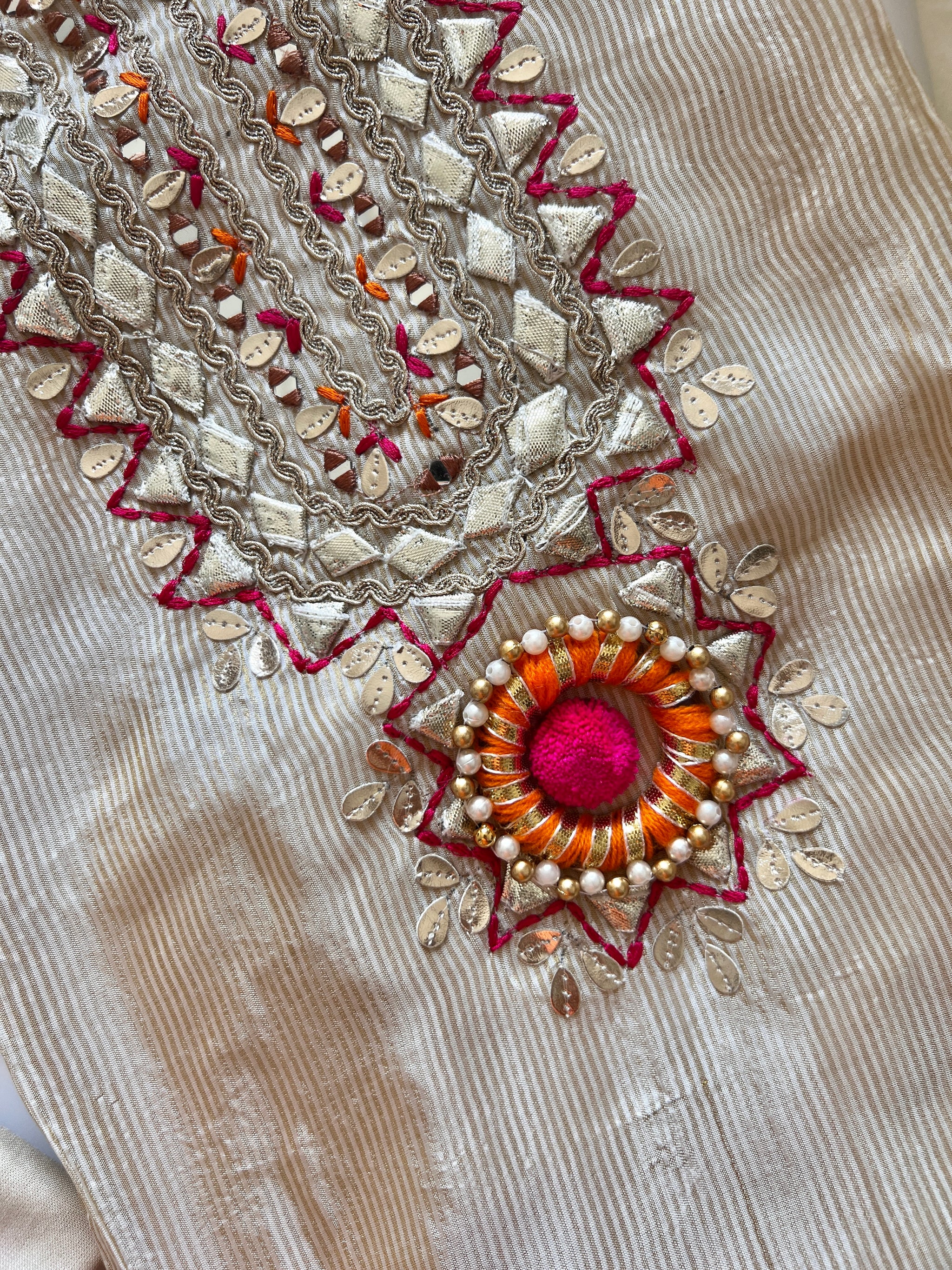 Festive cream dress material with neck embroidery, soft tissue fabric and decorative pom pom latkans