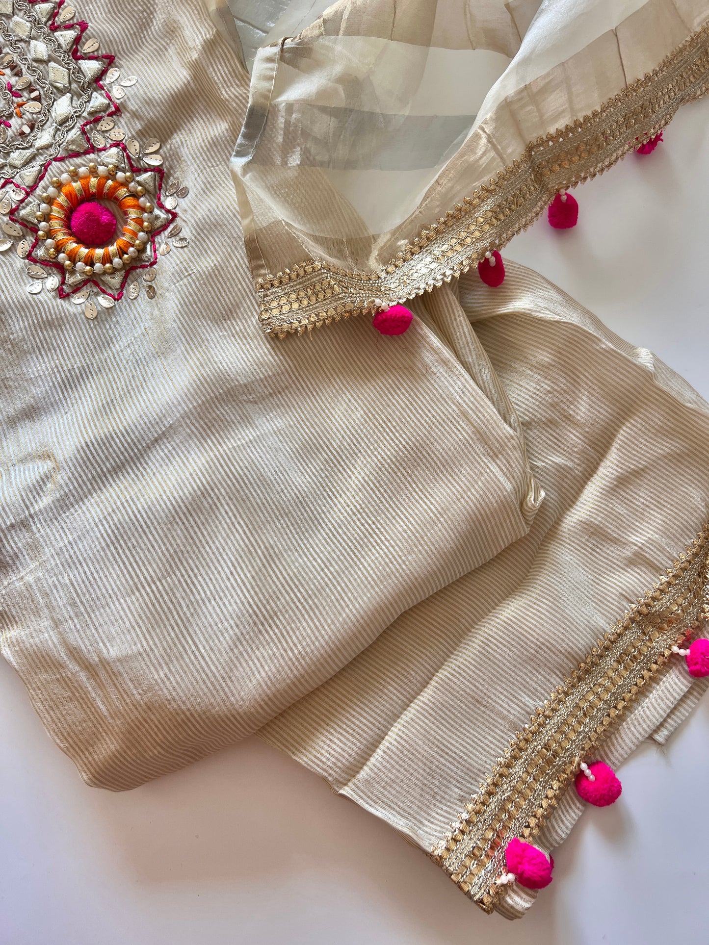 Cream unstitched salwar suit material in tissue fabric with embroidered neckline and designer pom pom detailing